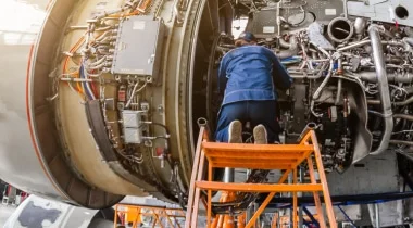A man performs maintenance on a jet engine